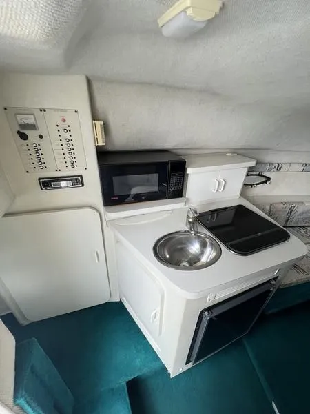 Slide: The Image of Compact kitchen area in a 2000 Glastron 249 boat with sink, stove, and microwave. - 7