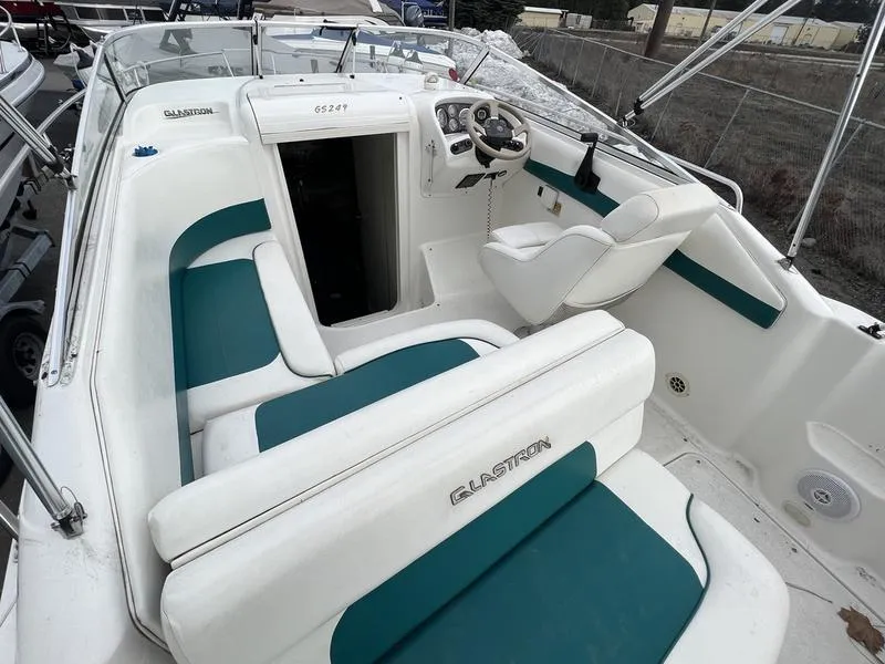 Slide: The Image of 2000 Glastron 249 boat interior with white and teal seating, steering wheel, and dashboard. - 8