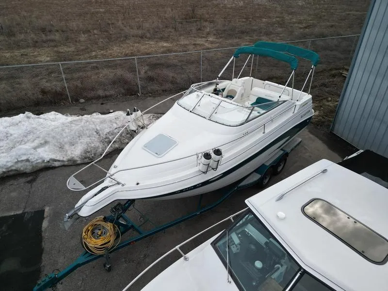 Slide: The Image of 2000 Glastron 249 boat on trailer, parked near a fence with snow nearby. - 9