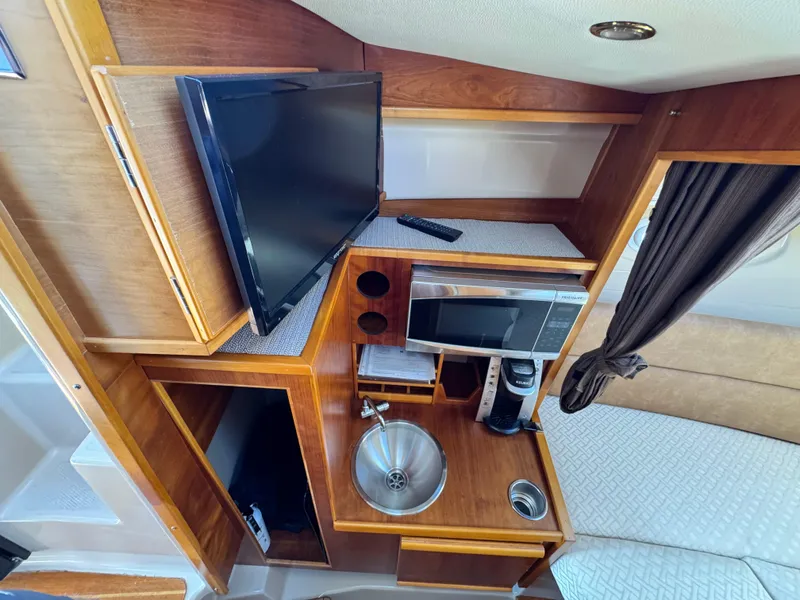 Slide: The Image of 2016 Cutwater C-28 interior with TV, microwave, sink, and wooden cabinetry. - 7