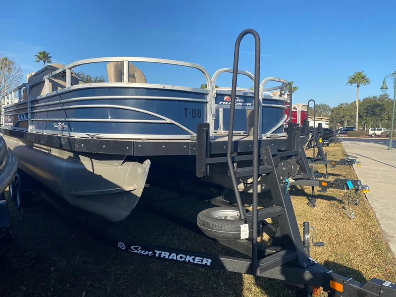 Slide: The Image of 2021 Sun Tracker Fishin' Barge 22 DLX pontoon boat on trailer, parked outdoors. - 3