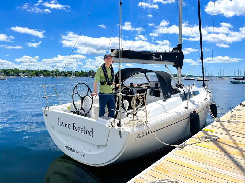 Slide: The Image of 2018 Hanse 315 sailboat docked, sunny day, person onboard, "Even Keeled" on stern. - 2