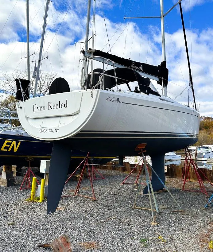 Slide: The Image of 2018 Hanse 315 sailboat on stands, Kingston, NY, under a partly cloudy sky. - 25