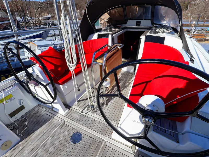 Slide: The Image of 2018 Hanse 315 yacht cockpit with dual steering wheels and vibrant red seating. - 5
