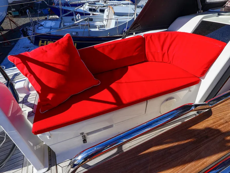Slide: The Image of Red cushioned seating on 2018 Hanse 315 yacht deck, with marina background. - 7
