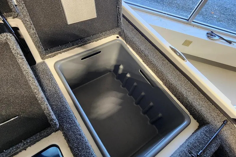 Slide: The Image of 2025 Nitro Z20 XL boat storage compartment with carpeted interior and open lid. - 13