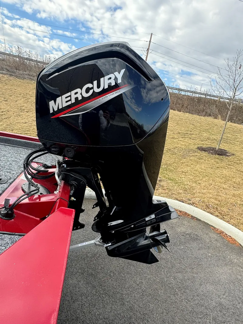 Slide: The Image of 2025 Tracker Pro Team 175 with Mercury outboard motor, parked on pavement. - 7
