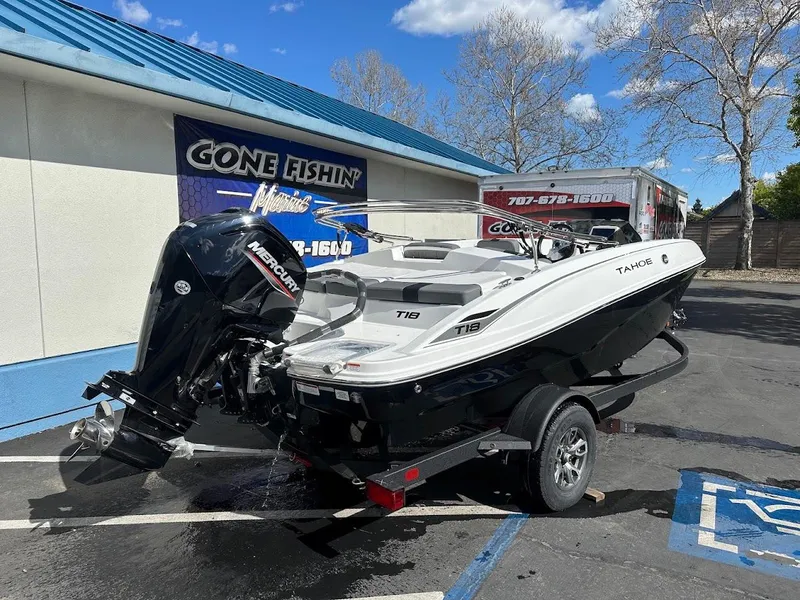 Slide: The Image of 2025 Tahoe T18 boat on trailer, parked outside Gone Fishin' Marine store. - 1