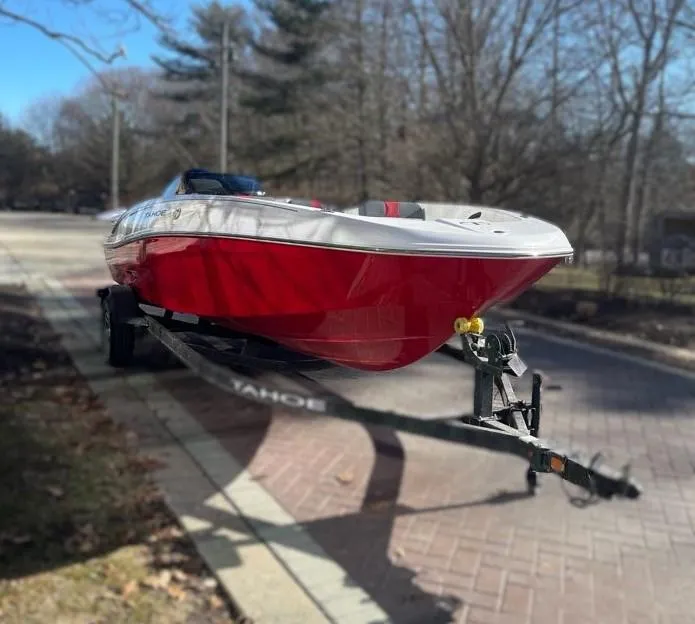 Slide: The Image of 2025 Tahoe T18 boat on trailer, parked on a sunny street. - 2