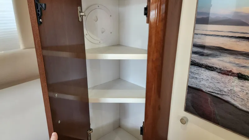 Slide: The Image of Open cabinet with wooden door and shelves inside a 2008 Carver 36 Mariner boat. - 37