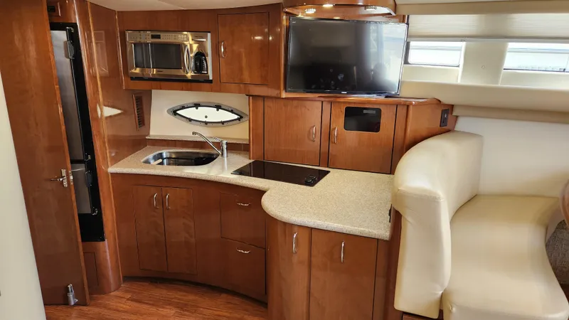 Slide: The Image of 2008 Carver 36 Mariner interior with kitchenette, featuring wood cabinetry, sink, and seating area. - 38