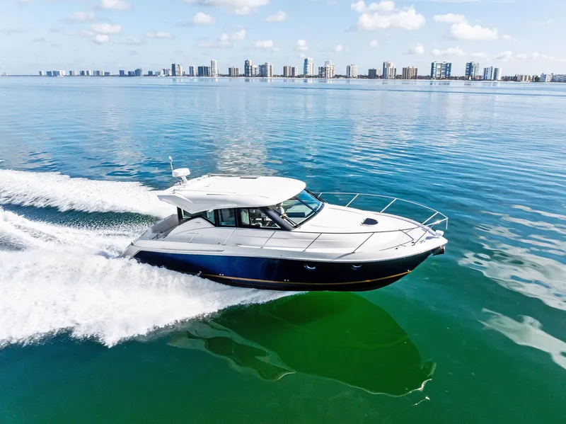 Slide: The Image of 2019 Tiara Yachts 39 Coupe cruising on calm waters with city skyline in background. - 16