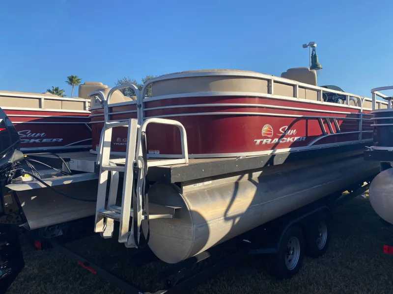 Slide: The Image of 2020 Sun Tracker Party Barge 24 DLX pontoon boat on trailer, red and white design. - 2