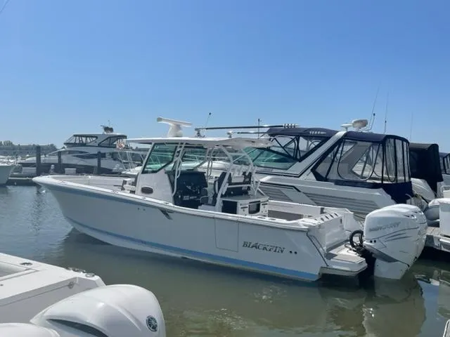 Slide: The Image of 2022 Blackfin 332 CC boat docked at marina under clear blue sky. - 13