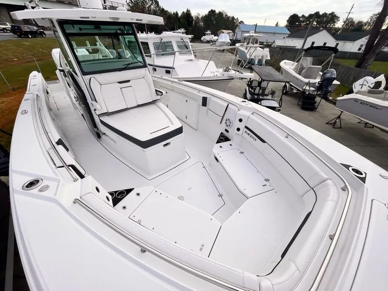 Slide: The Image of 2022 Blackfin 332 CC boat with spacious seating and sleek design in a marina setting. - 9