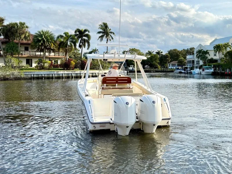 Slide: The Image of 2016 Pursuit S 280 Sport boat cruising on a scenic, palm-lined waterway. - 2