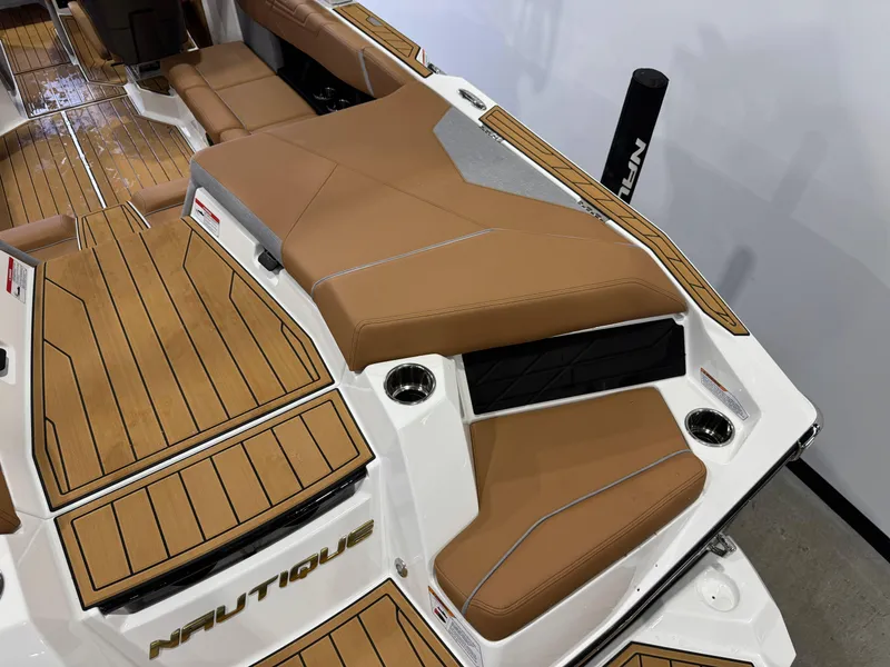 Slide: The Image of 2025 Nautique Super Air Nautique S23 interior with tan seating and teak flooring. - 11