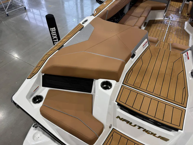 Slide: The Image of 2025 Nautique Super Air Nautique S23 boat interior with tan seating and wood accents. - 12