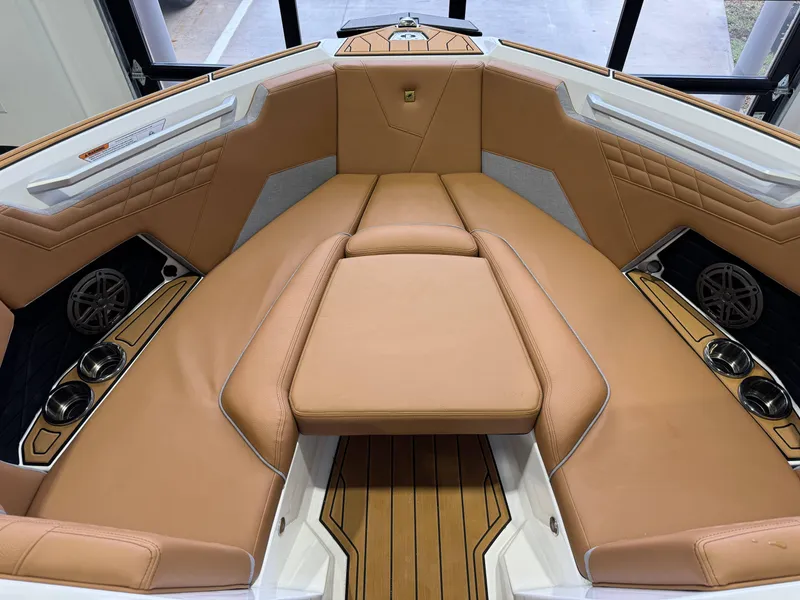 Slide: The Image of 2025 Nautique Super Air Nautique S23 interior with tan leather seating and cup holders. - 17
