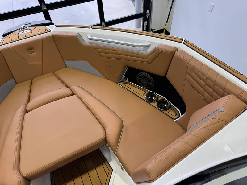 Slide: The Image of 2025 Nautique Super Air Nautique S23 interior with tan leather seating and cup holders. - 18