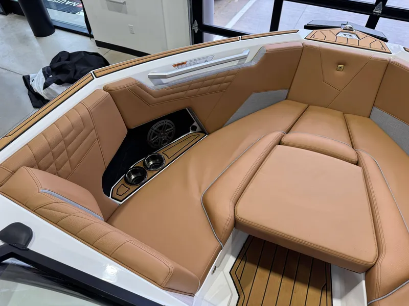 Slide: The Image of 2025 Nautique Super Air Nautique S23 interior with tan leather seating and cup holders. - 19