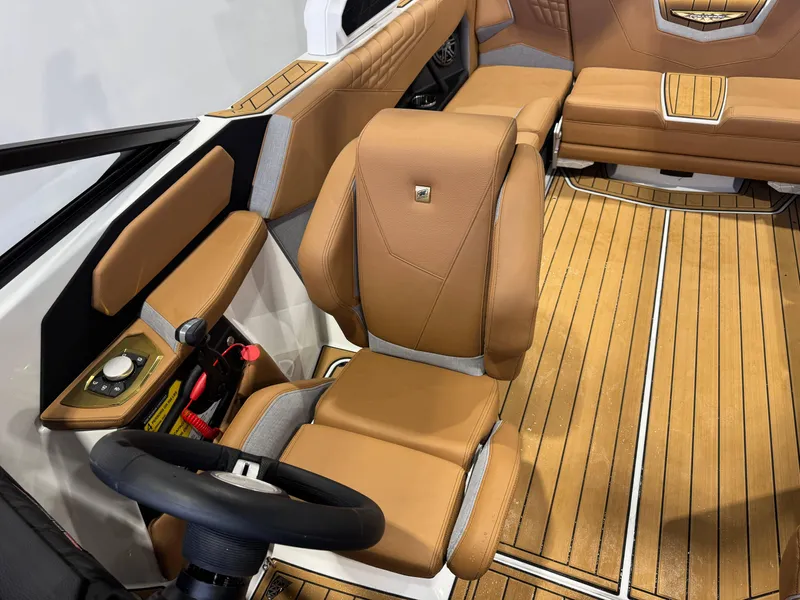 Slide: The Image of 2025 Nautique Super Air Nautique S23 interior with tan leather seating and wood flooring. - 21