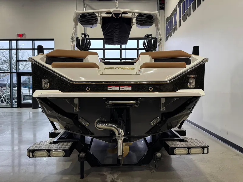 Slide: The Image of 2025 Nautique Super Air Nautique S23 boat, rear view in showroom setting. - 6