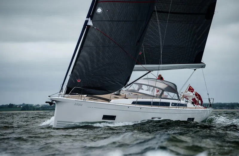 Slide: The Image of 2026 X-Yachts X4 9 sailing on open water with dark sails and sleek design. - 2