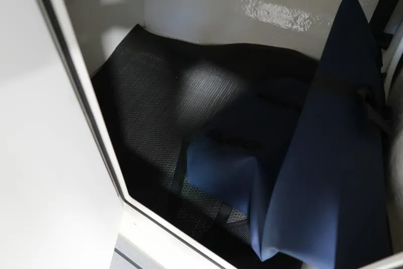 Slide: The Image of Interior storage compartment of 2025 Chaparral 21 SSi boat, featuring dark mat and blue cover. - 29