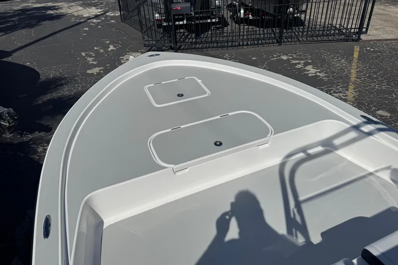 Slide: The Image of 2026 Shallow Sport 22 Sport boat deck with storage compartments, parked on asphalt. - 18