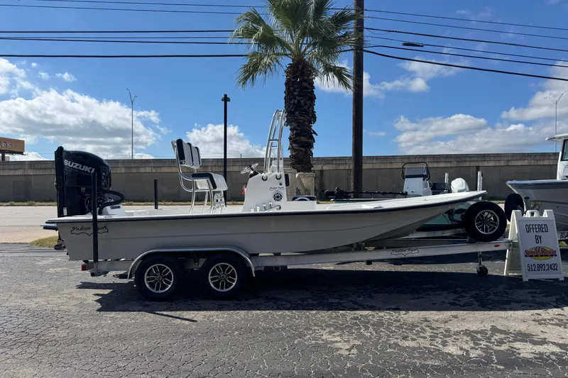 Slide: The Image of 2026 Shallow Sport 22 Sport boat on trailer, parked outdoors under clear sky. - 26