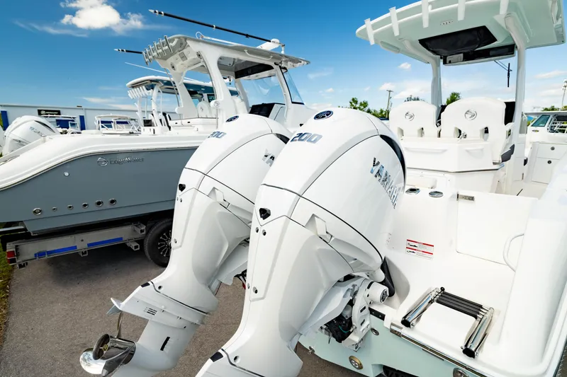 Slide: The Image of 2025 Edgewater 262CC boat with dual outboard engines, parked on a sunny day. - 10