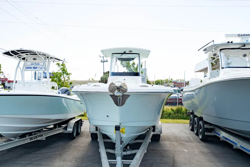 Slide: The Image of 2025 Edgewater 262CC boat on trailer, flanked by two other boats. - 11