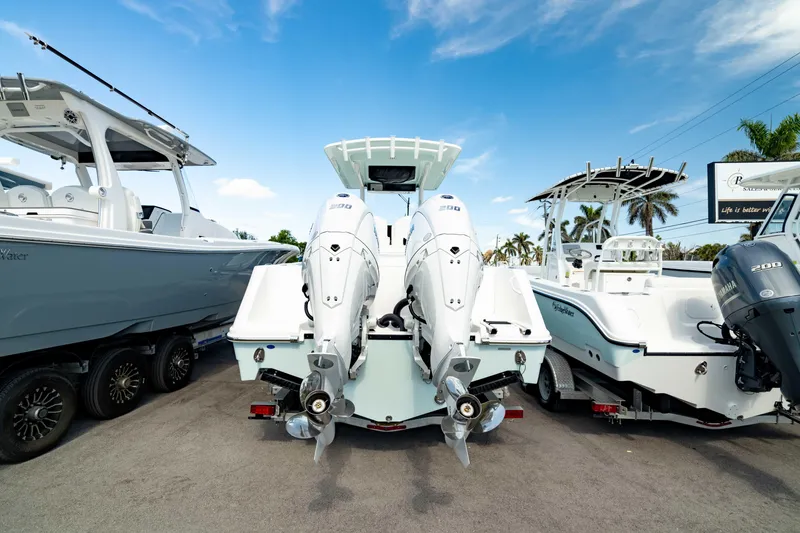 Slide: The Image of 2025 Edgewater 262CC boat with dual outboard engines, parked among other boats. - 12