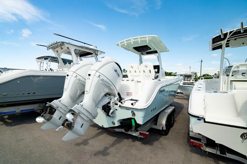 Slide: The Image of 2025 Edgewater 262CC boat with dual engines on a trailer, parked outdoors. - 18