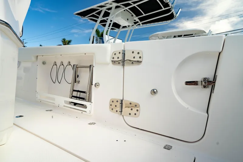 Slide: The Image of 2025 Edgewater 262CC boat interior, featuring storage compartment and ladder under a clear blue sky. - 24
