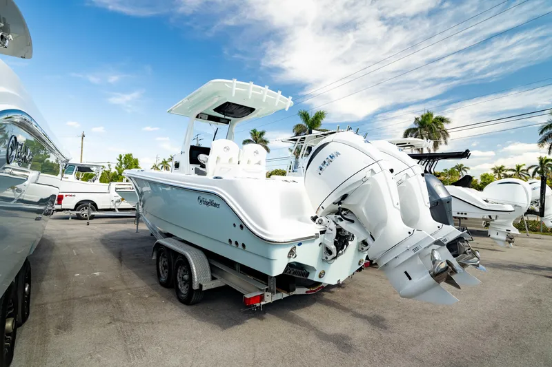 Slide: The Image of 2025 Edgewater 262CC boat on trailer, featuring dual outboard engines, parked outdoors. - 27