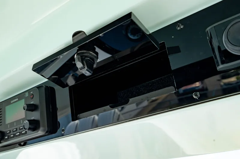 Slide: The Image of 2025 Edgewater 262CC boat dashboard with open storage compartment and electronic controls. - 39