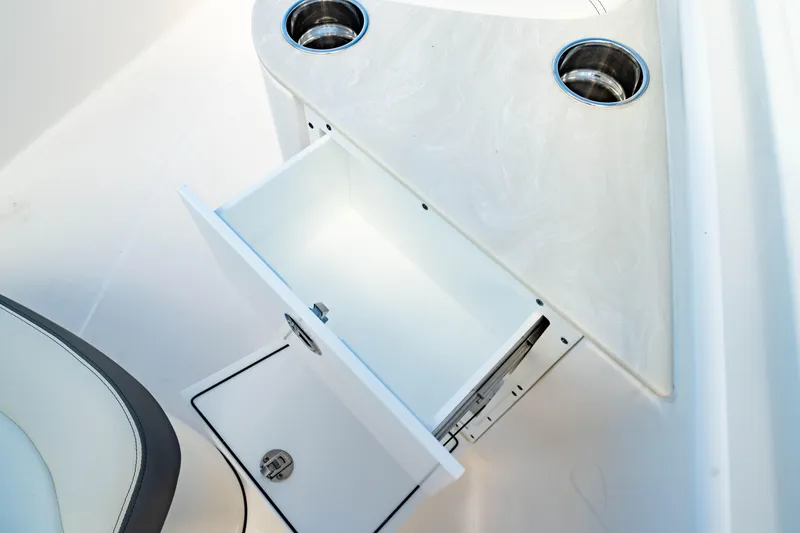Slide: The Image of 2025 Edgewater 262CC boat interior with open storage drawer and cup holders. - 45
