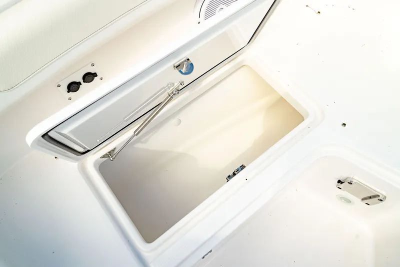 Slide: The Image of 2025 Edgewater 262CC boat storage compartment, open lid, white interior. - 48