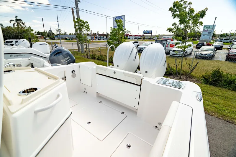 Slide: The Image of 2025 Edgewater 262CC boat interior with dual engines, parked outdoors near a road and parking lot. - 8