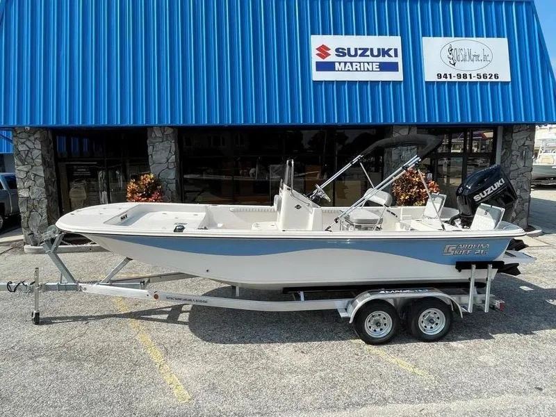 Slide: The Image of 2025 Carolina Skiff 21 LS boat on trailer outside Suzuki Marine dealership. - 1