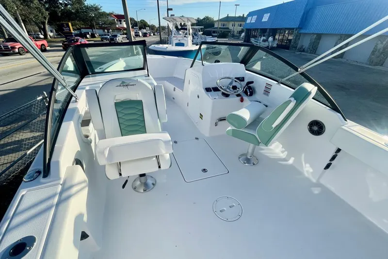Slide: The Image of 2024 Aquasport 2200 DC boat interior with green and white seating, steering wheel, and dashboard. - 4