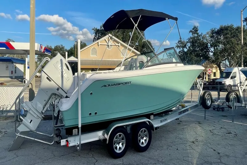 Slide: The Image of 2024 Aquasport 2200 DC boat on trailer, featuring a sleek design and outboard motor. - 9