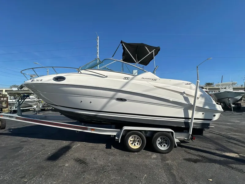 Slide: The Image of 2010 Sea Ray 240 Sundancer boat on trailer, parked outdoors under clear blue sky. - 1