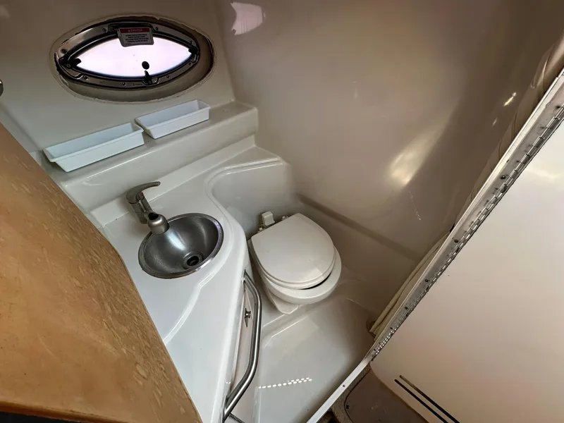 Slide: The Image of 2010 Sea Ray 240 Sundancer bathroom with sink, toilet, and porthole window. - 11