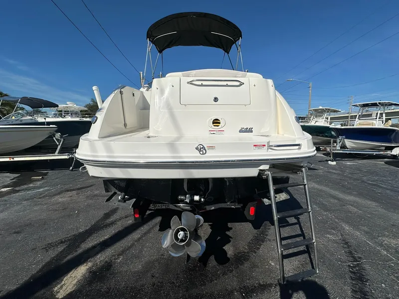 Slide: The Image of 2010 Sea Ray 240 Sundancer boat, rear view with ladder and propeller, parked outdoors. - 3