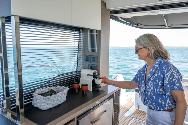 Slide: The Image of Woman using coffee machine on Jeanneau NC 1295 Coupe yacht, 2025 model, with ocean view. - 17