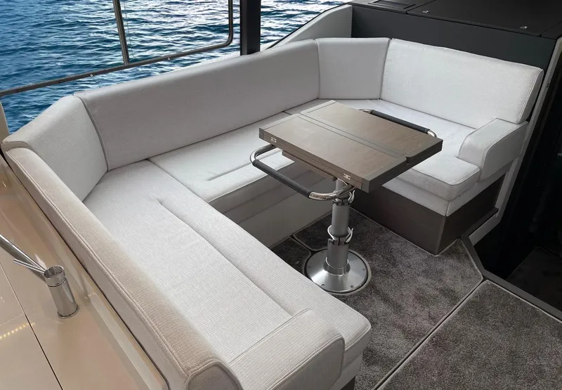 Slide: The Image of 2025 Jeanneau NC 1295 Coupe interior with elegant seating and table, overlooking the water. - 18