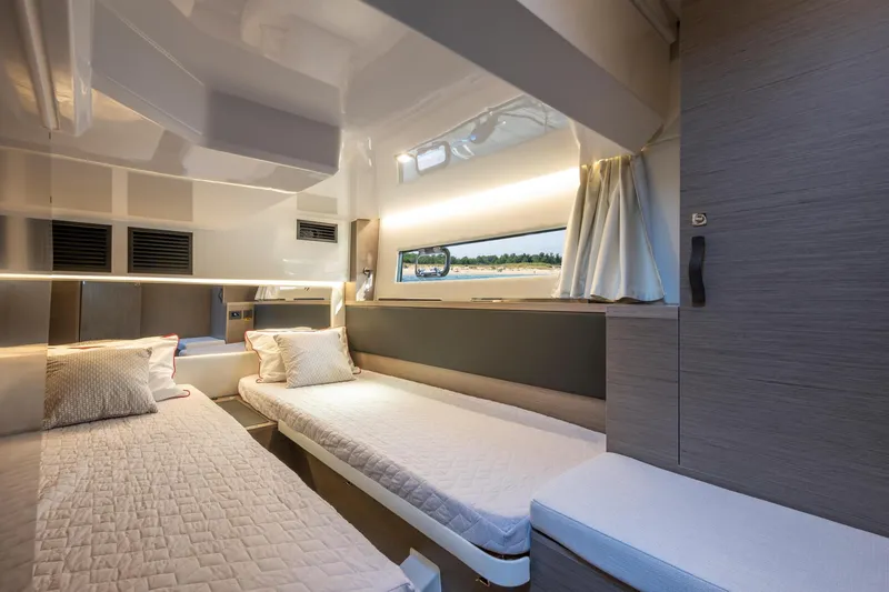 Slide: The Image of Interior of 2025 Jeanneau NC 1295 Coupe, featuring twin beds and modern design. - 23